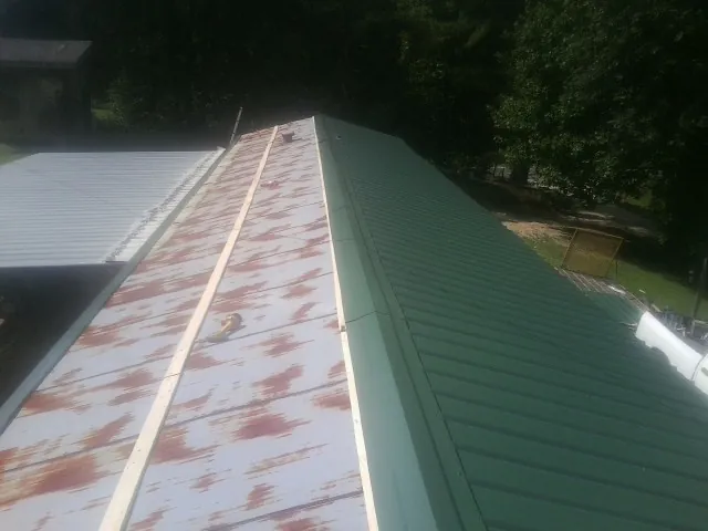 Old rusted panels beside newly installed green metal roofing — Wind Damage Roof Repair by Roofing Brothers in Rio Linda