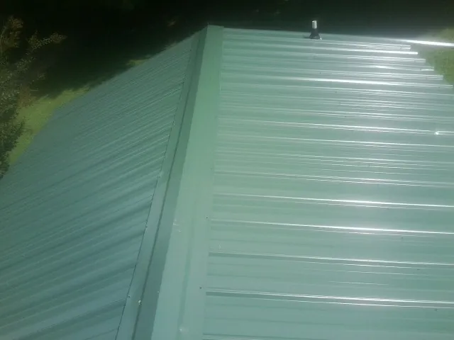 New green metal panels meeting at the ridge of a roof — Flat Roof Repair work by our crew in Rio Linda