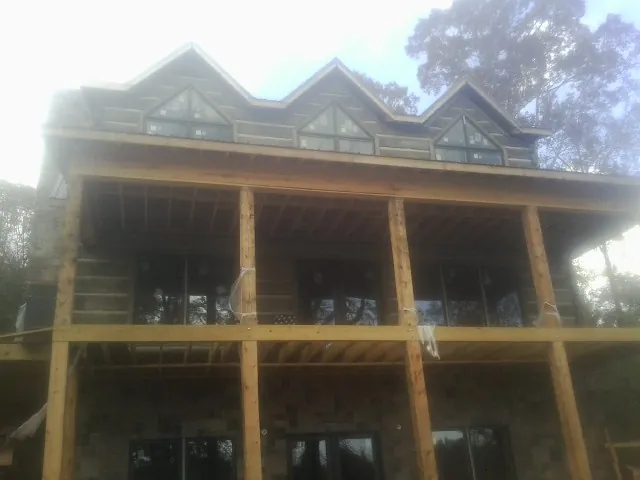 Dormers and porch framing on a large log home under construction — Roof Coating work by our crew in Rio Linda