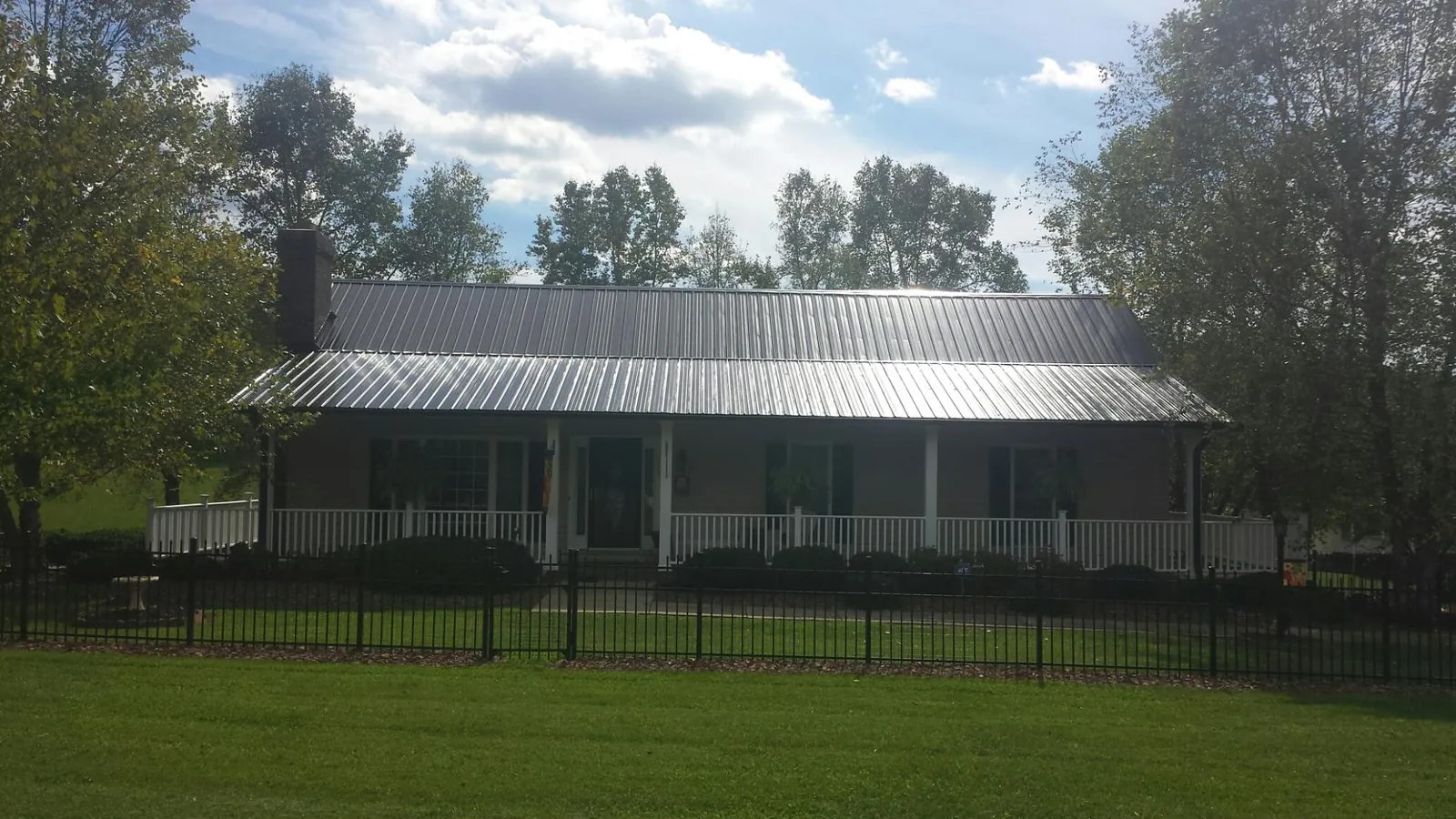 Gray metal roof on a brick ranch with a full width front porch — Gutter Guard Installation work by our crew in Rio Linda