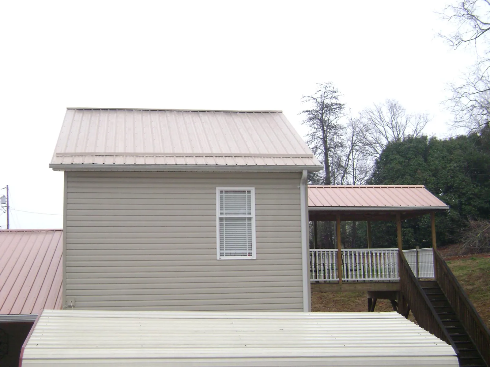 Tan metal roofs on a two story addition and attached porch, from a Roof Replacement job in Rio Linda