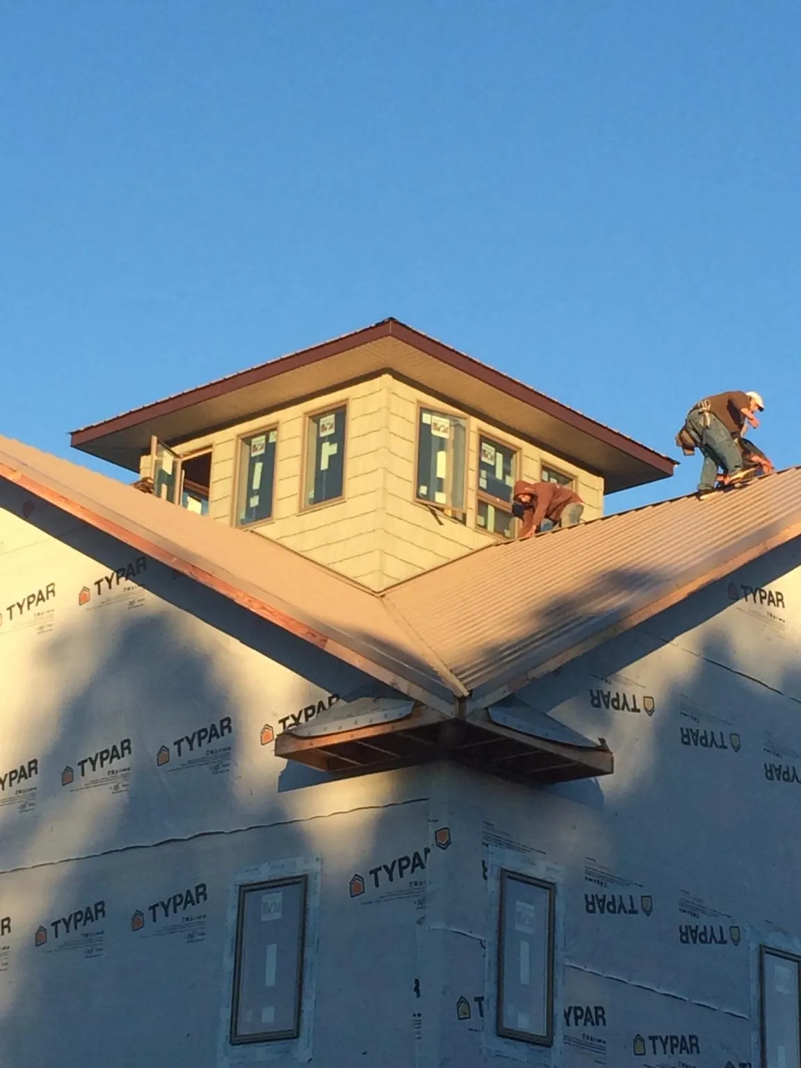 Roofers working around a rooftop cupola on a new metal roof at sunset — Roof Waterproofing in Rio Linda by Roofing Brothers